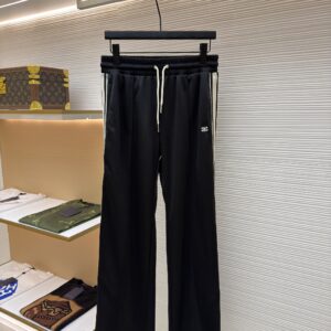 A pair of black Celine track trousers with cream side stripes hanging in a luxury boutique.