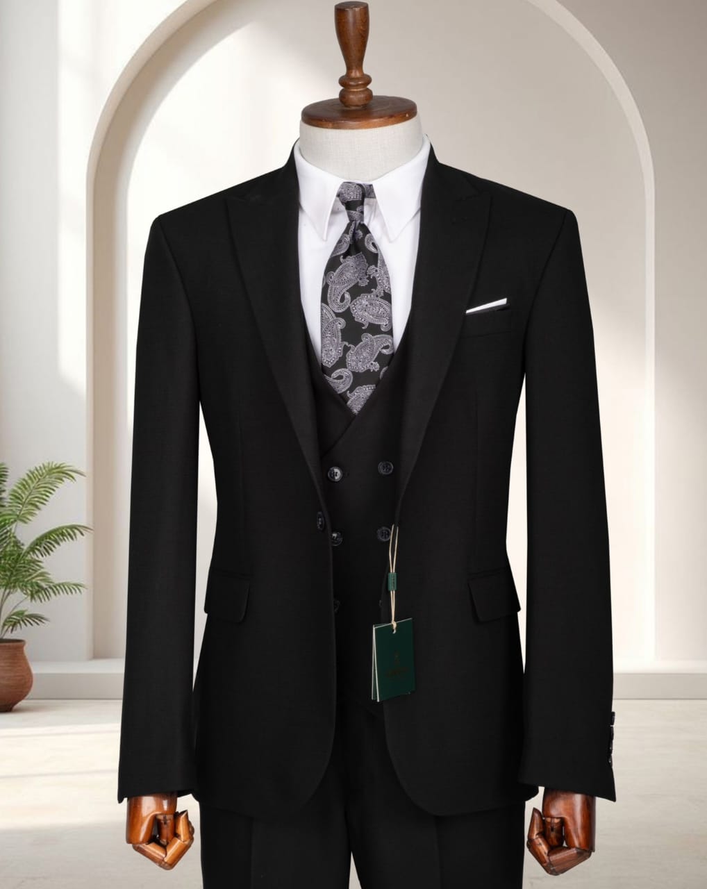 A premium classic black three-piece single-breasted suit with a double-breasted waistcoat, white shirt, and paisley tie displayed on a mannequin.