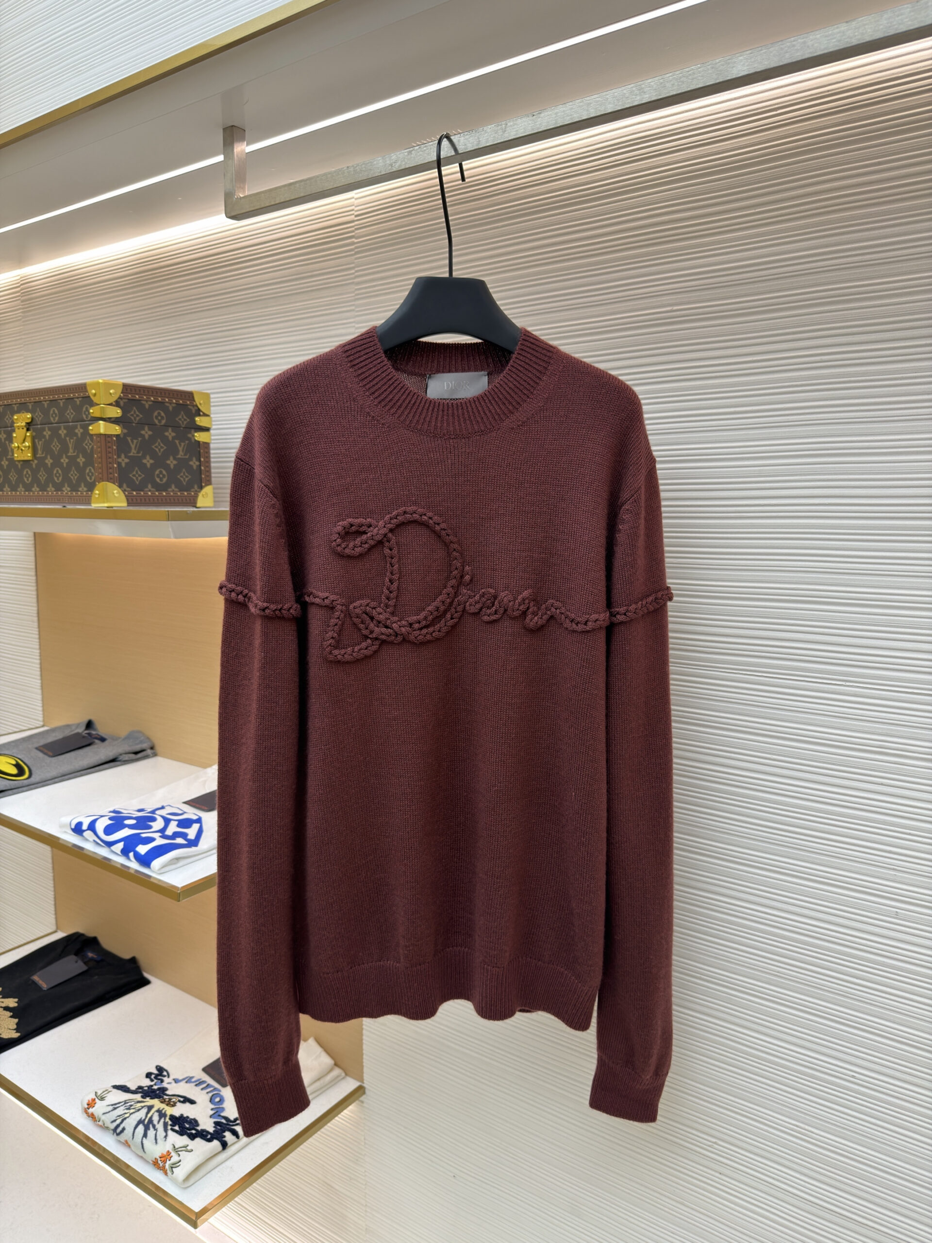 A luxury Dior Brown Braided Logo Sweater displayed on a black hanger, showing the front view with braided rope detailing.