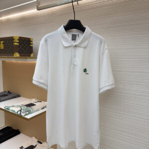 A premium Dior White Clover Embroidery Polo Shirt in white, hanging on a black hanger, displaying the green four-leaf clover and "Dior" signature on the chest.