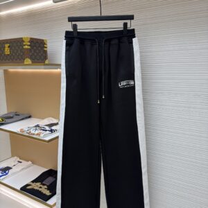 A pair of black Louis Vuitton wide-leg joggers with white textured side stripes hanging in a luxury boutique.