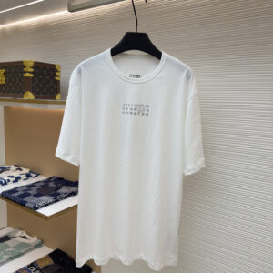 A white MM6 Maison Margiela t-shirt hanging in a luxury boutique.