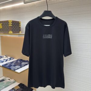 A black MM6 Maison Margiela t-shirt displayed in a luxury setting.