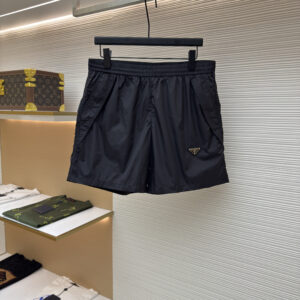 Front view of black Prada technical nylon shorts featuring an enameled triangle logo hanging on a display rack.