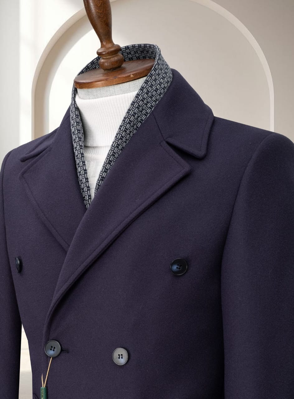 A men's navy blue double-breasted formal overcoat with matching dark buttons on a wooden mannequin.