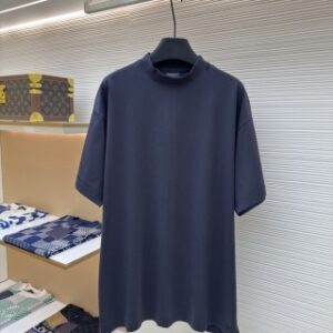 A men's Balenciaga dark navy oversized washed cotton t-shirt with a red tape logo on the back hanging on a clothes rail.