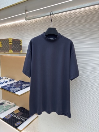 A men's Balenciaga dark navy oversized washed cotton t-shirt with a red tape logo on the back hanging on a clothes rail.