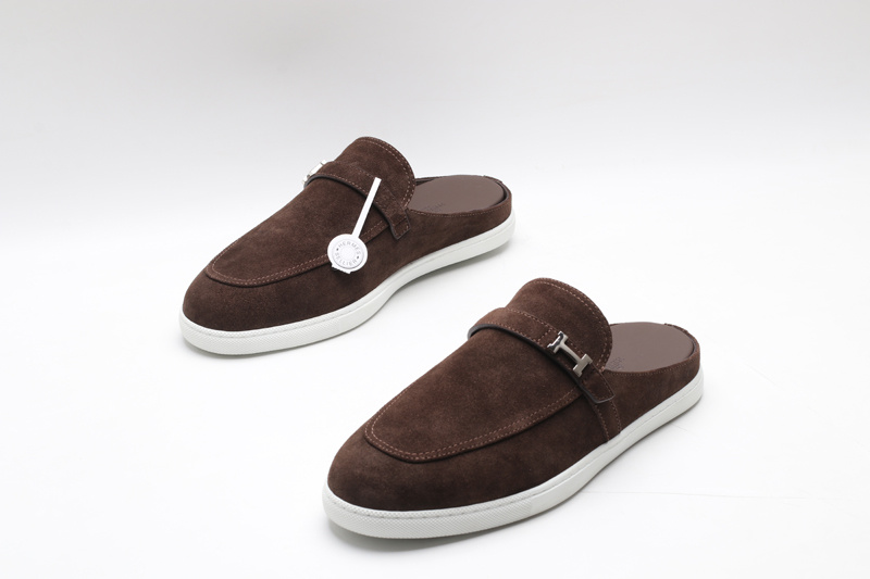 Dark brown suede slip-on mules with an apron toe and white rubber soles on a white background.
