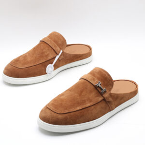 Tan suede slip-on mules with an apron toe and white rubber soles on a white background.