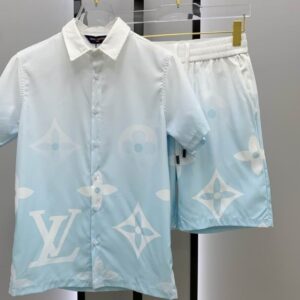 A men's matching two-piece casual set featuring a light blue and white gradient short-sleeve button-up shirt and shorts with large white monogram patterns.