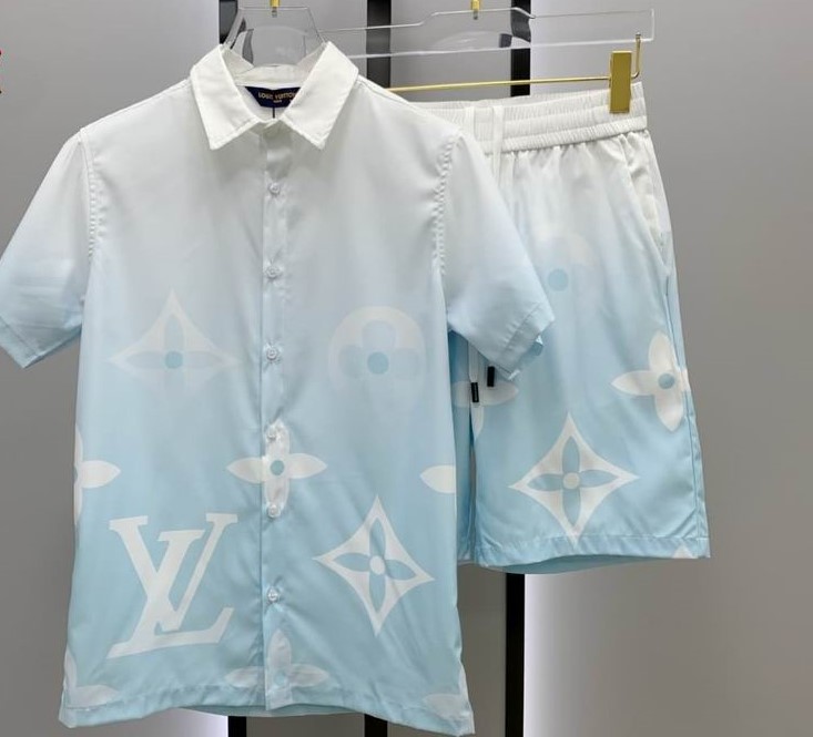 A men's matching two-piece casual set featuring a light blue and white gradient short-sleeve button-up shirt and shorts with large white monogram patterns.