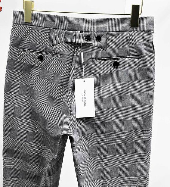 A men's light grey plaid two-piece suit with a windowpane check pattern, featuring a two-button jacket and matching trousers hanging on a black display rack.