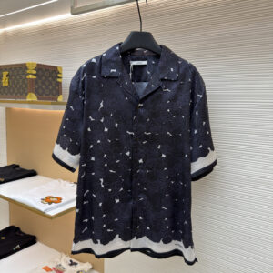 Front view of a Givenchy Midnight Rose Print Silk Short-Sleeve Shirt hanging in a luxury boutique, featuring a black rose pattern and white border.