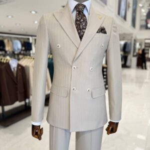 Man wearing a beige pinstripe double breasted suit with peak lapels and tapered trousers
